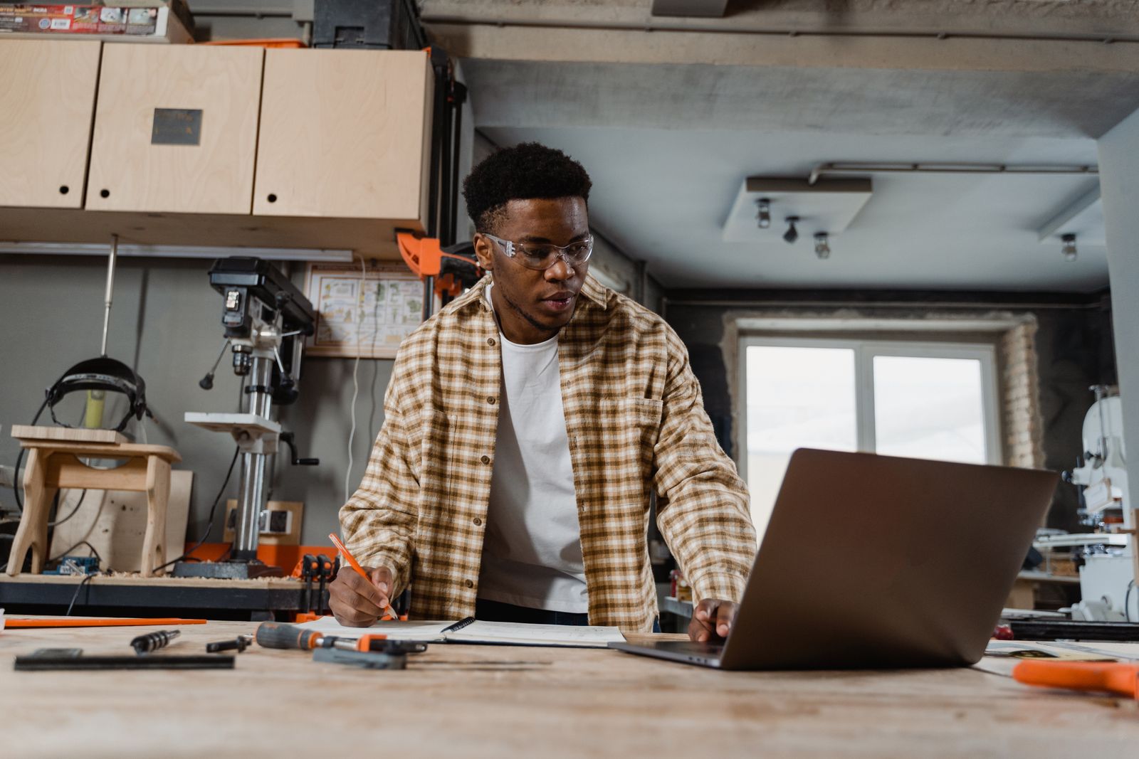 A carpenter reviewing work records with a laptop at a workbench